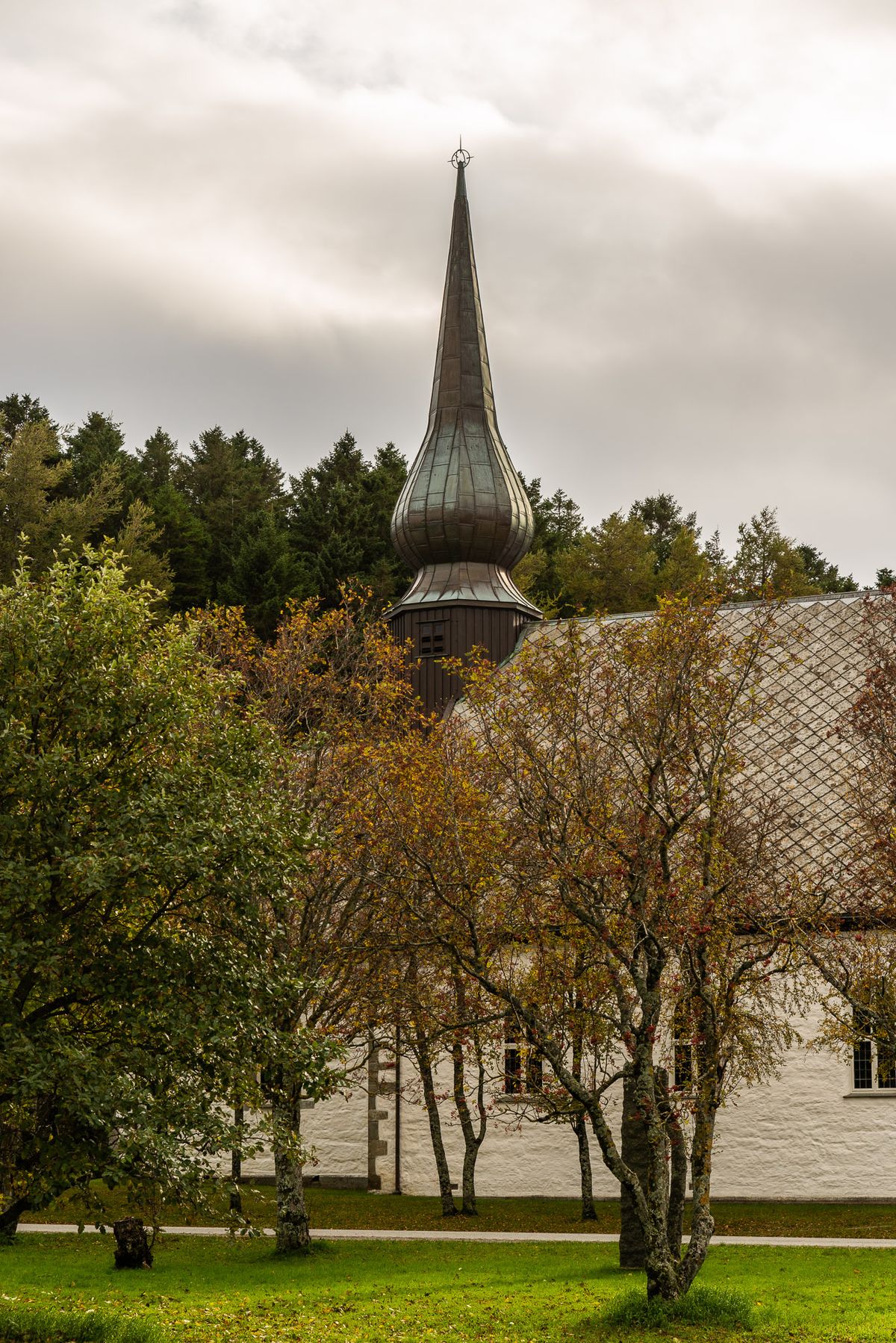 Foto av kirkens gårdsplass en høstdag. Tårnet i fokus.