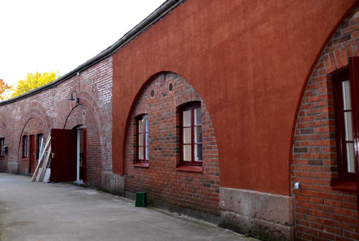 Foto av fasadedetaljer ved rehabilitering. Rød puss og rød tegl møtes i buer.