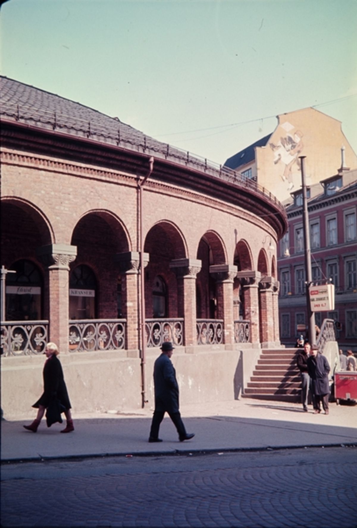 Historisk foto fra 1966 som viser gateliv med gående mennesker og Kirkeristen i bakgrunnen.