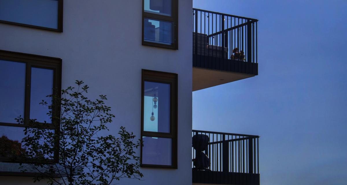 Kveldsfotografi av blå fasade, fokus på vinduer og balkonger.