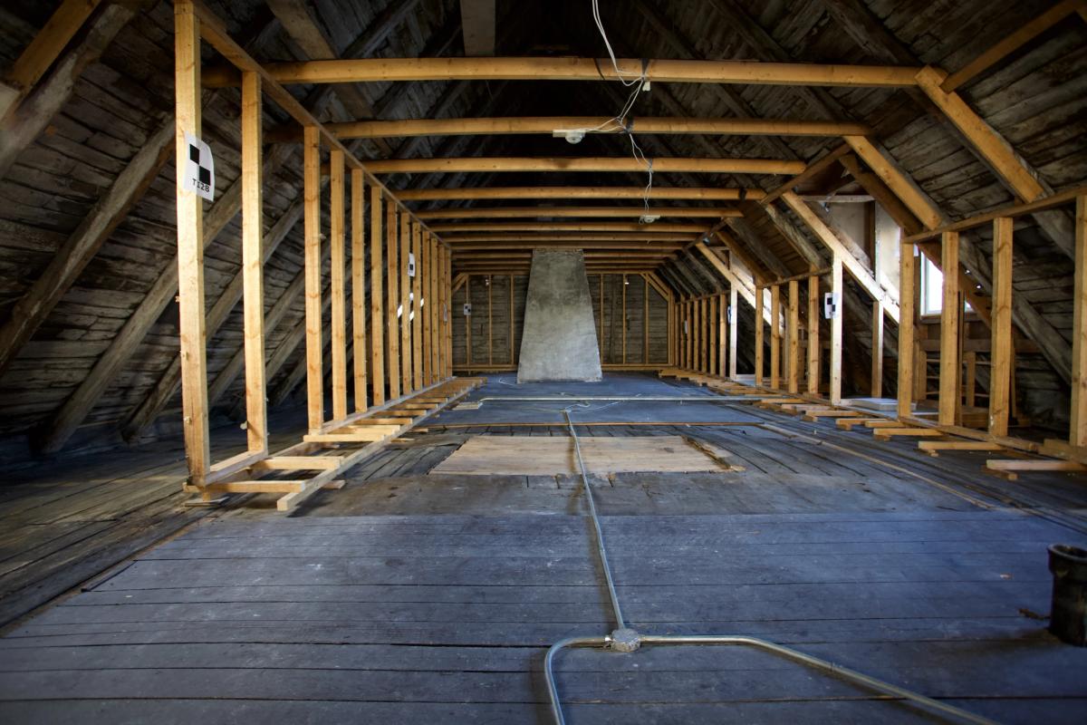 Foto av loftet under ombygging. Murt pipe står midtstilt i rommet.
