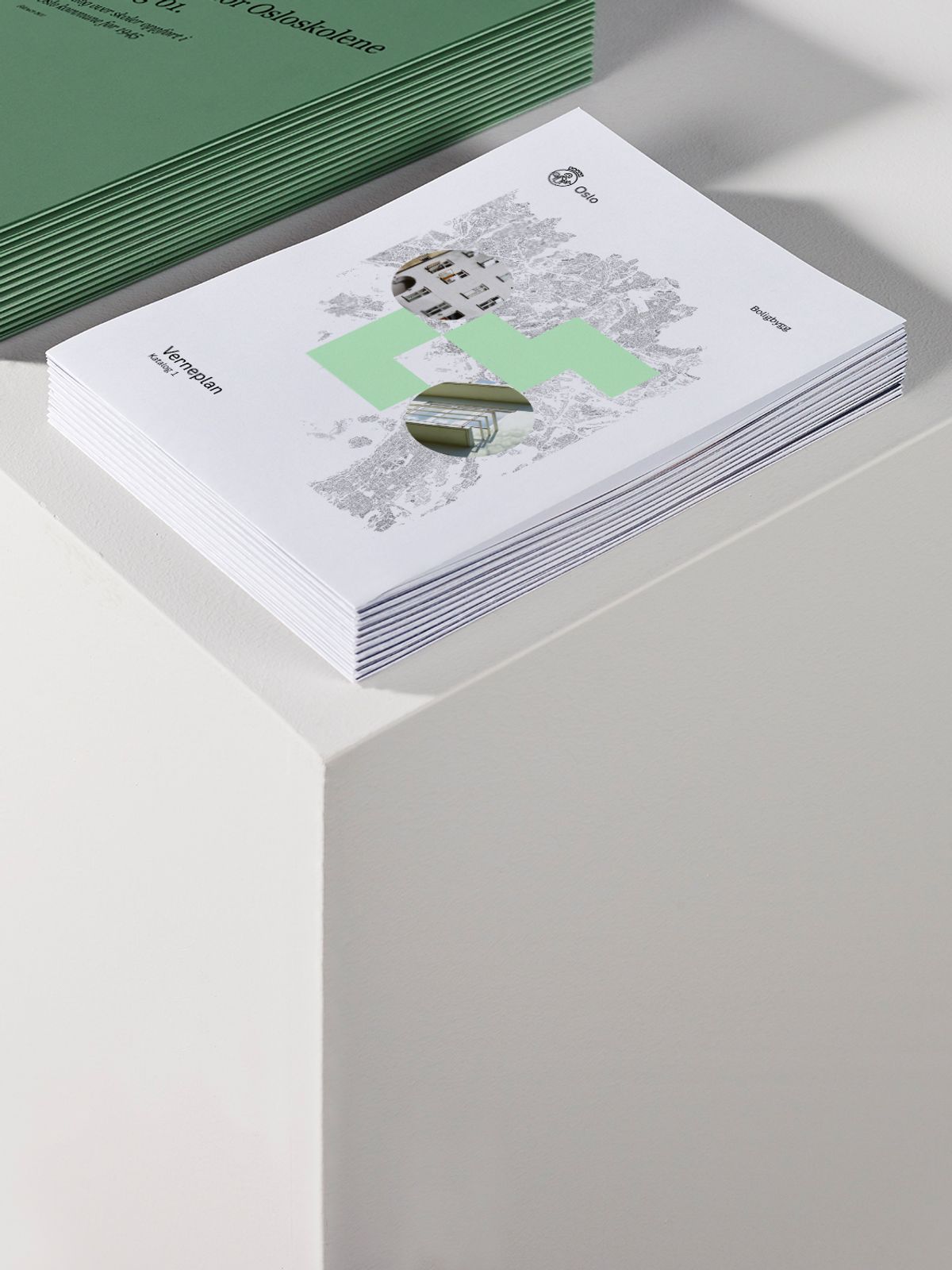Foto av bunke med rapporter, en bunke med hvite kataloger og en bunke med grønne kataloger oppstilt på podium.