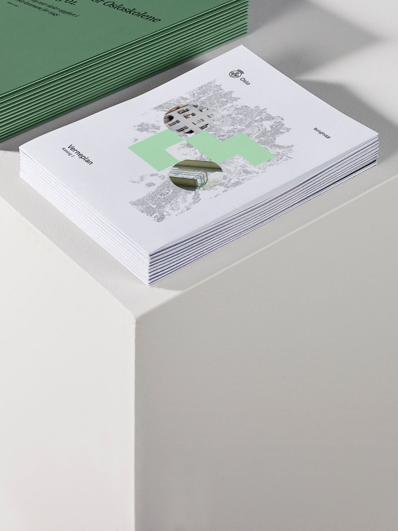 Foto av bunke med rapporter, en bunke med hvite kataloger og en bunke med grønne kataloger oppstilt på podium.