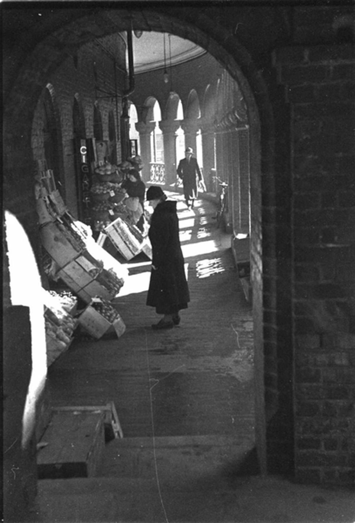 Historisk foto av butikksituasjon på Kirkeristen, kvinne ser på varer.