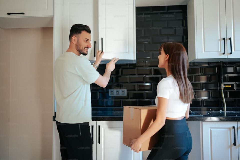 New homeowner organizing closing documents and warranty cards at kitchen table during move-in week