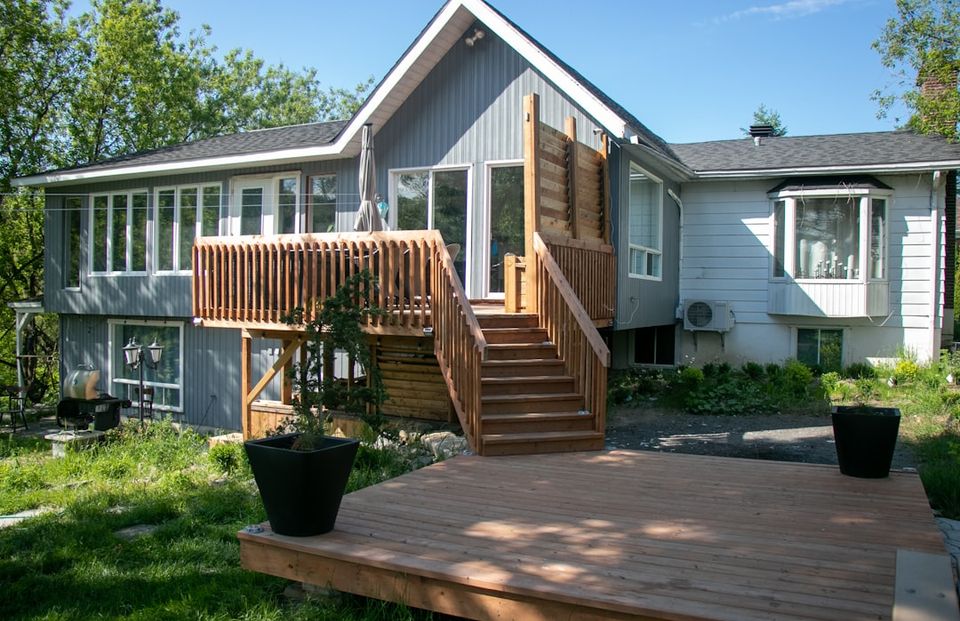 Elevated residential deck with stairs and wood substructure visible from the backyard, illustrating the ledger board inspection in a summer home maintenance checklist