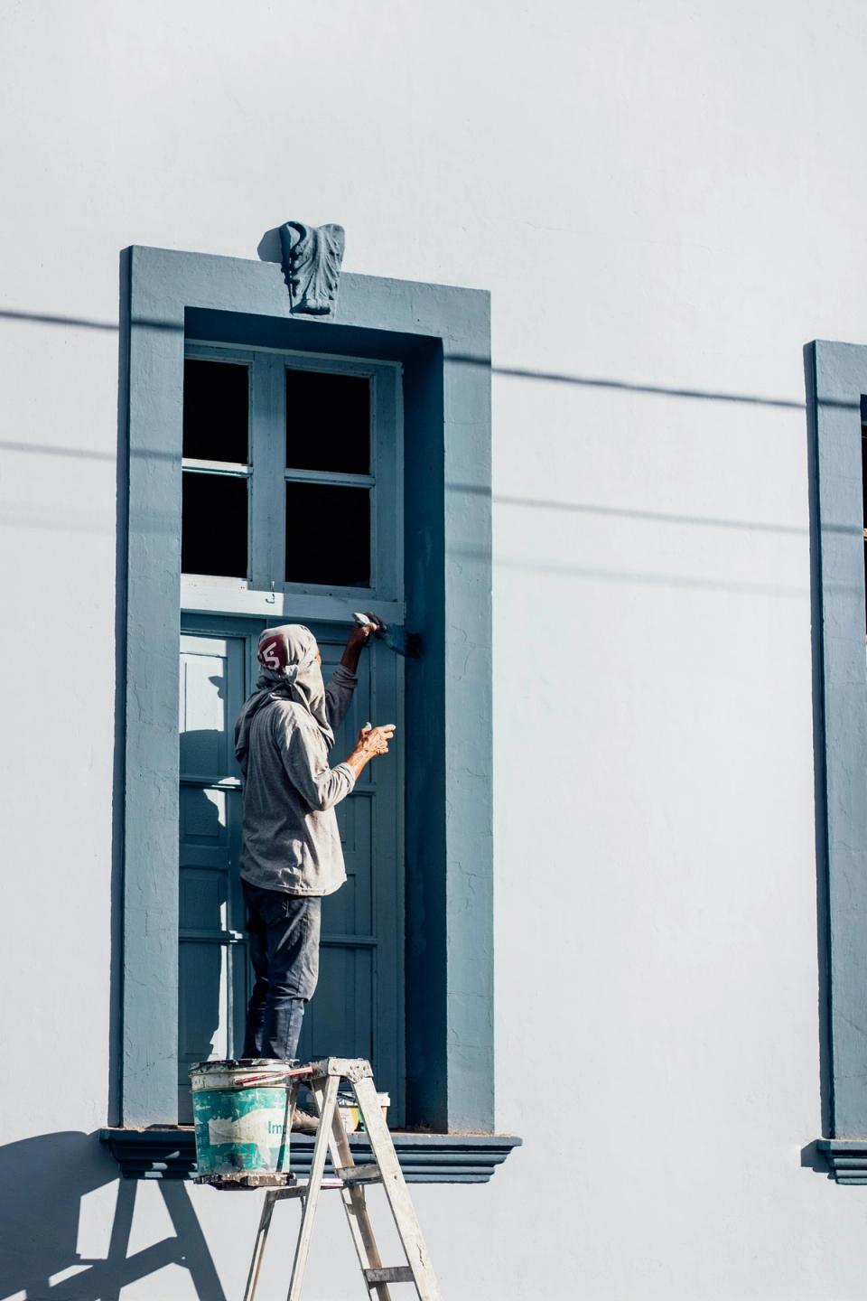 Homeowner touching up exterior door trim paint during spring home maintenance