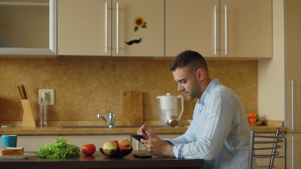 Homeowner checking maintenance reminders on a smartphone app in the kitchen