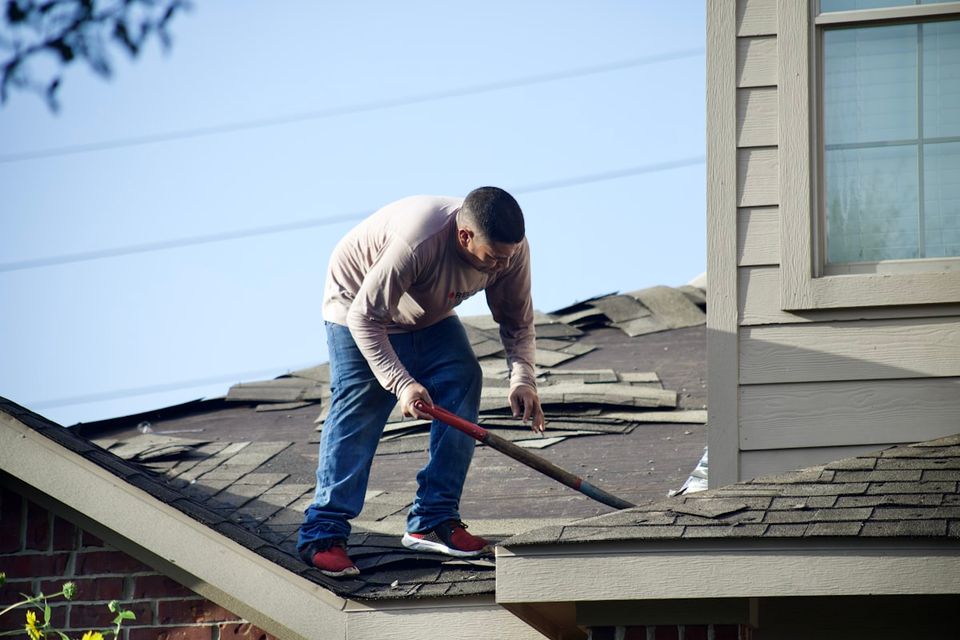 Homeowner inspecting roof shingles and gutters during spring maintenance using a seasonal checklist