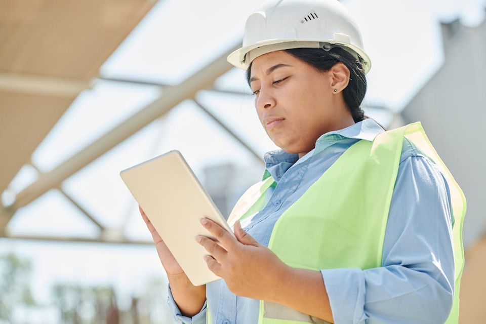 Construction project manager reviewing permit documents and inspection records on a tablet at a job site