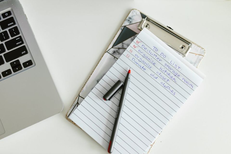 Home maintenance tracker spreadsheet open on a laptop with a paper log alongside