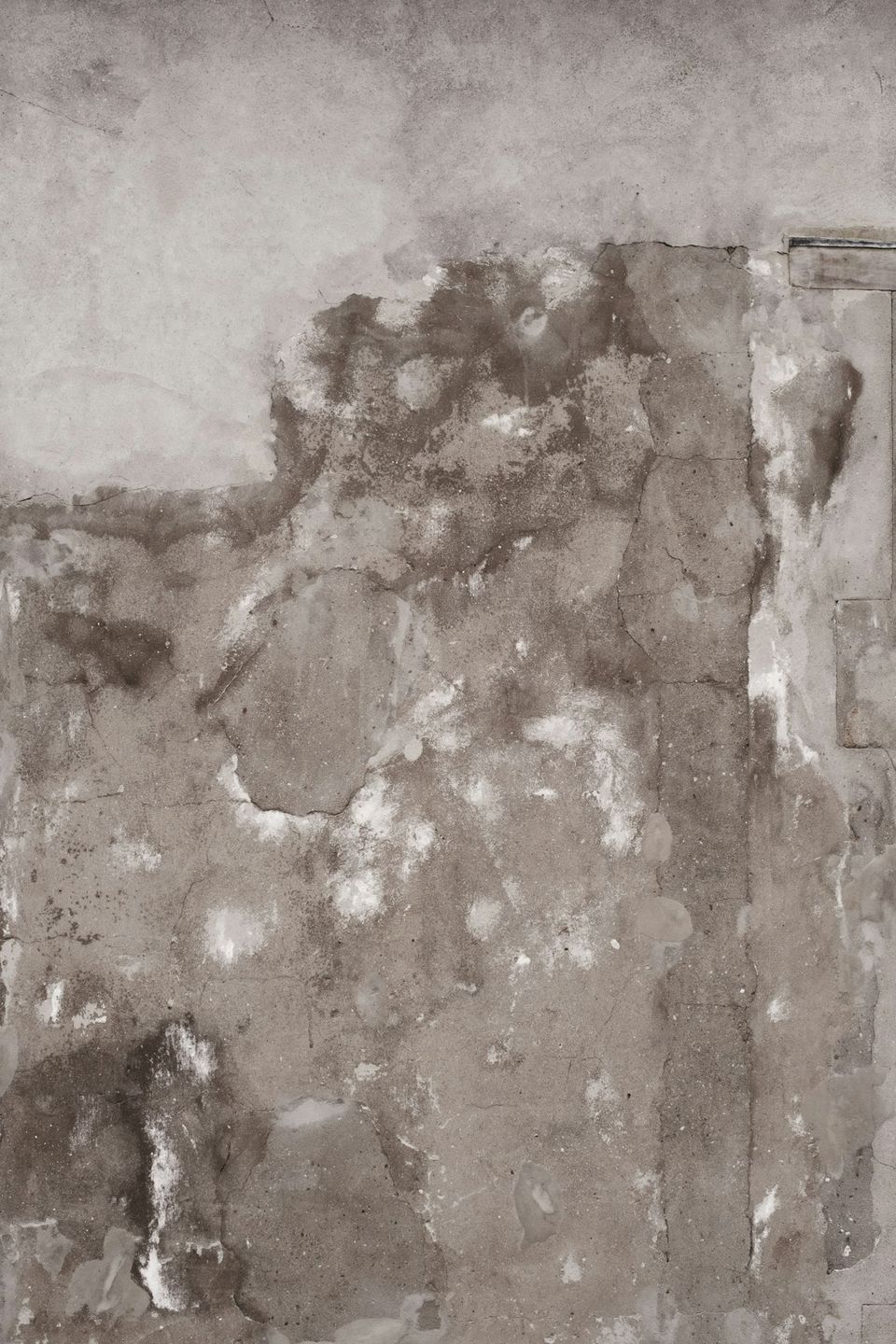 Homeowner photographing water damage in a kitchen for an insurance claim with date stamp visible