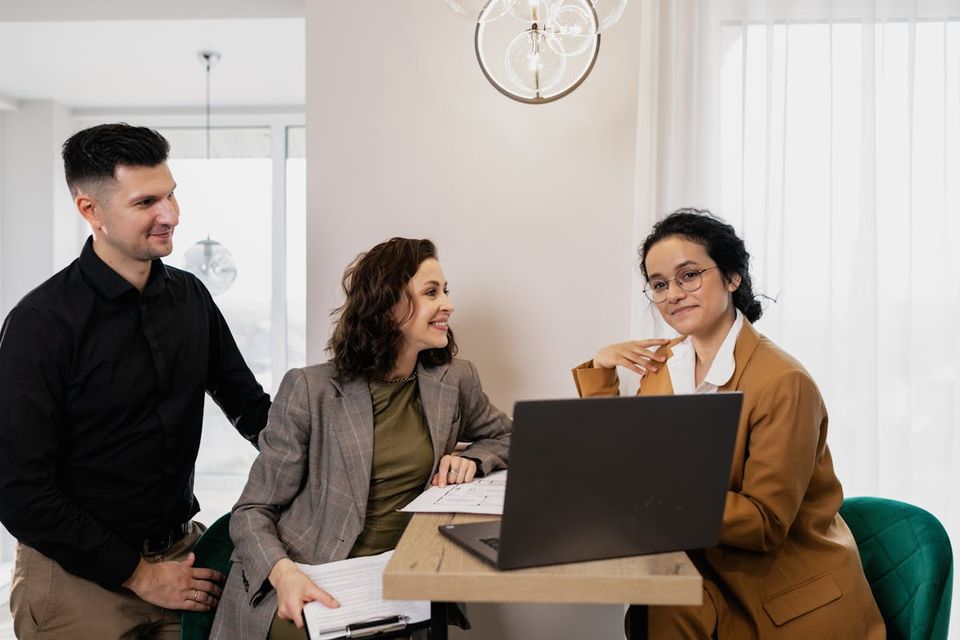 Listing agent presenting a property guidebook binder to sellers at a kitchen-table listing appointment