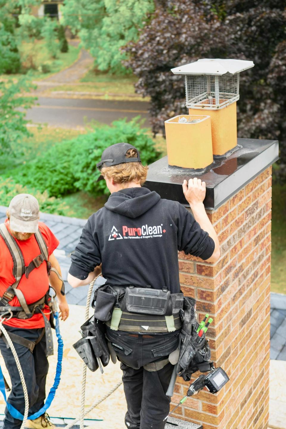 Workers inspecting a residential brick chimney exterior during fall home maintenance