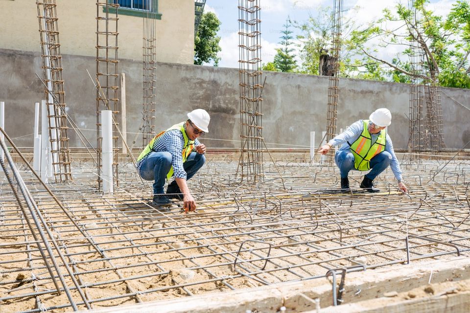 Construction site with permits posted and inspector reviewing foundation work