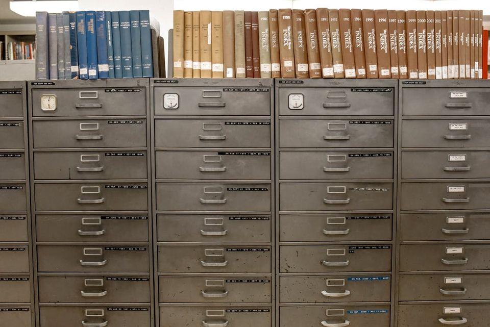 Comparison of physical filing cabinet versus digital document management on a laptop screen