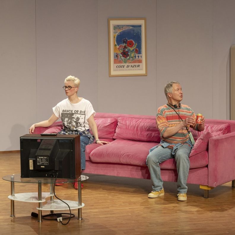 Пара на розовом диване в сцене, смотрят в стороны (Pari vaaleanpunaisella sohvalla lavalla, katsovat eri suuntiin)