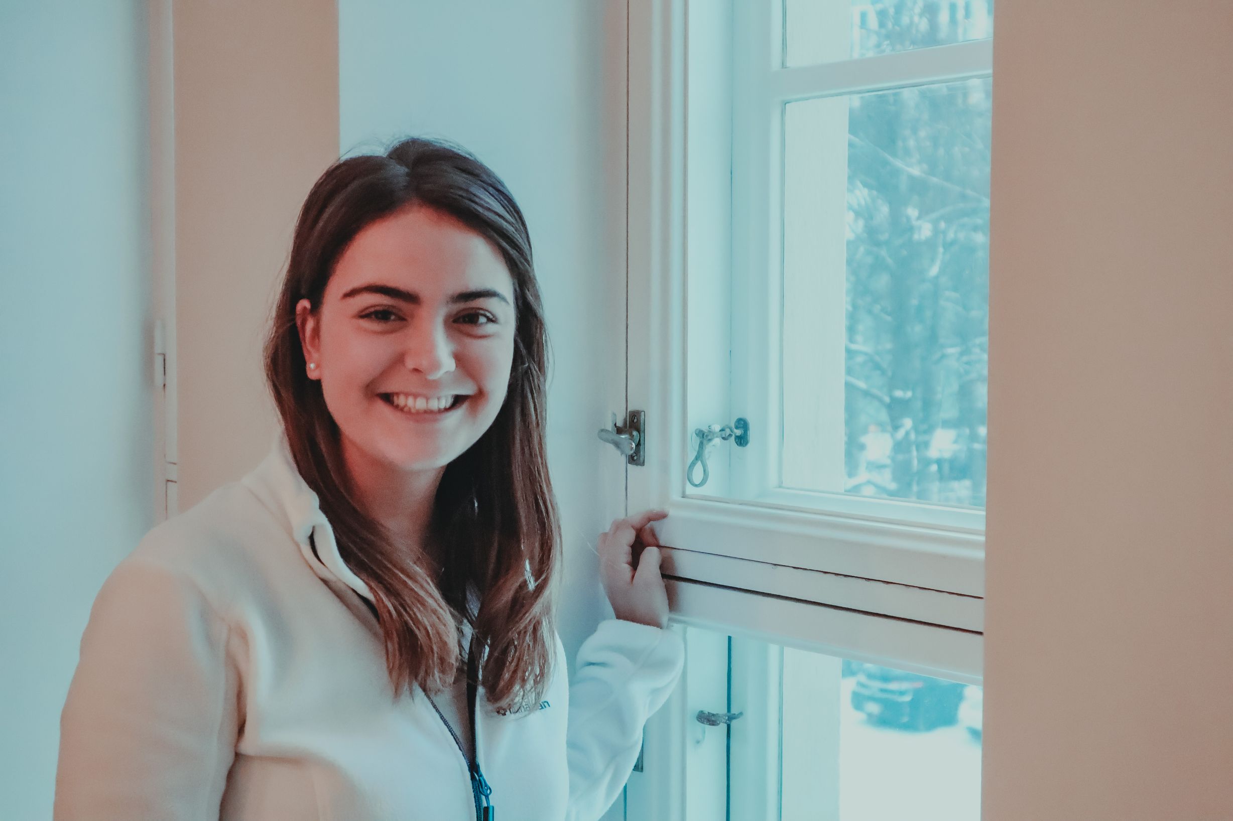 Madeleine Amoroso seisoo ikkunan vieressä hymyillen