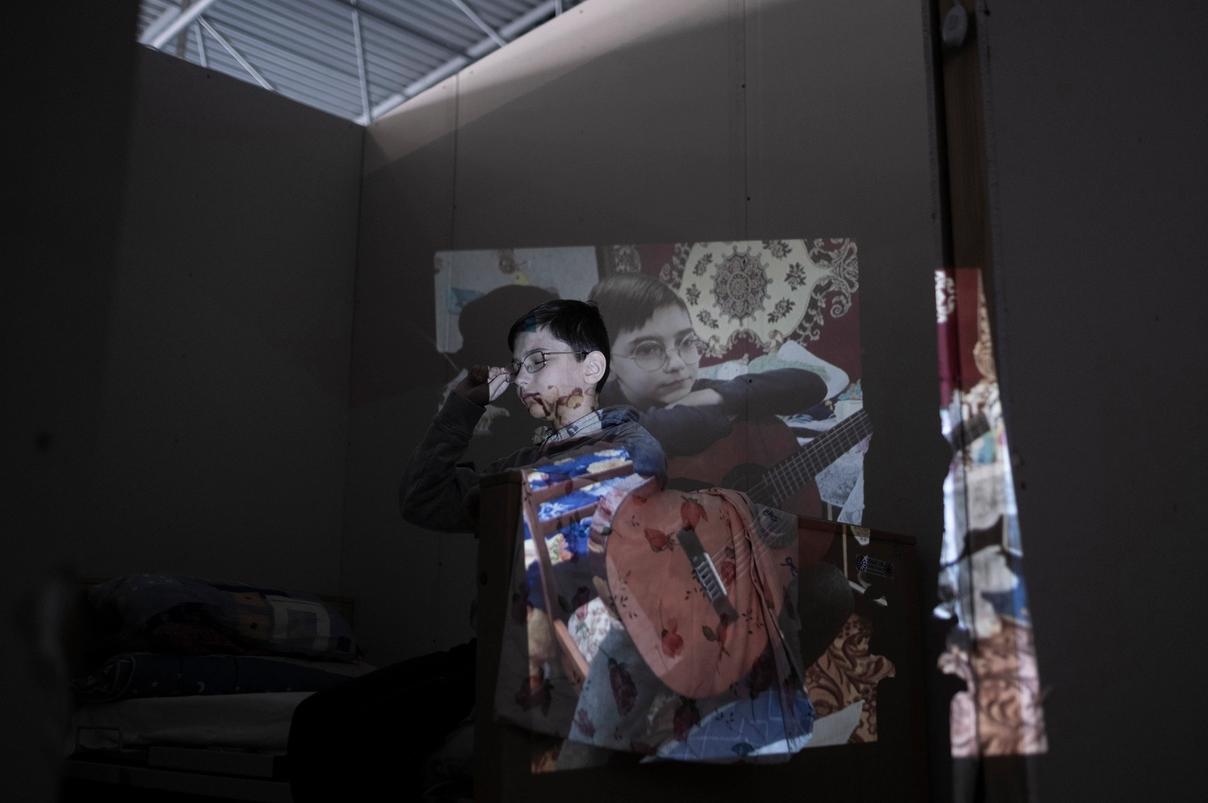 Мальчик с проекцией фотографии, где он играет на гитаре (Poika, jonka kasvoille heijastuu kuva hänestä soittamassa kitaraa)