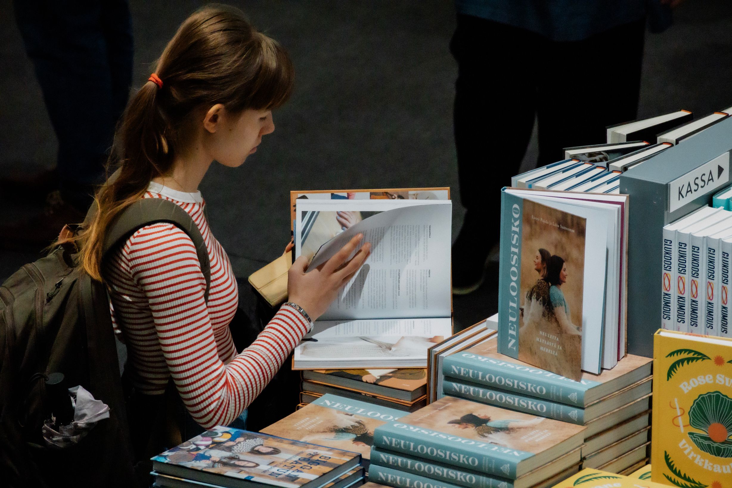 Nuori nainen selaa kirjaa kirjamessuilla