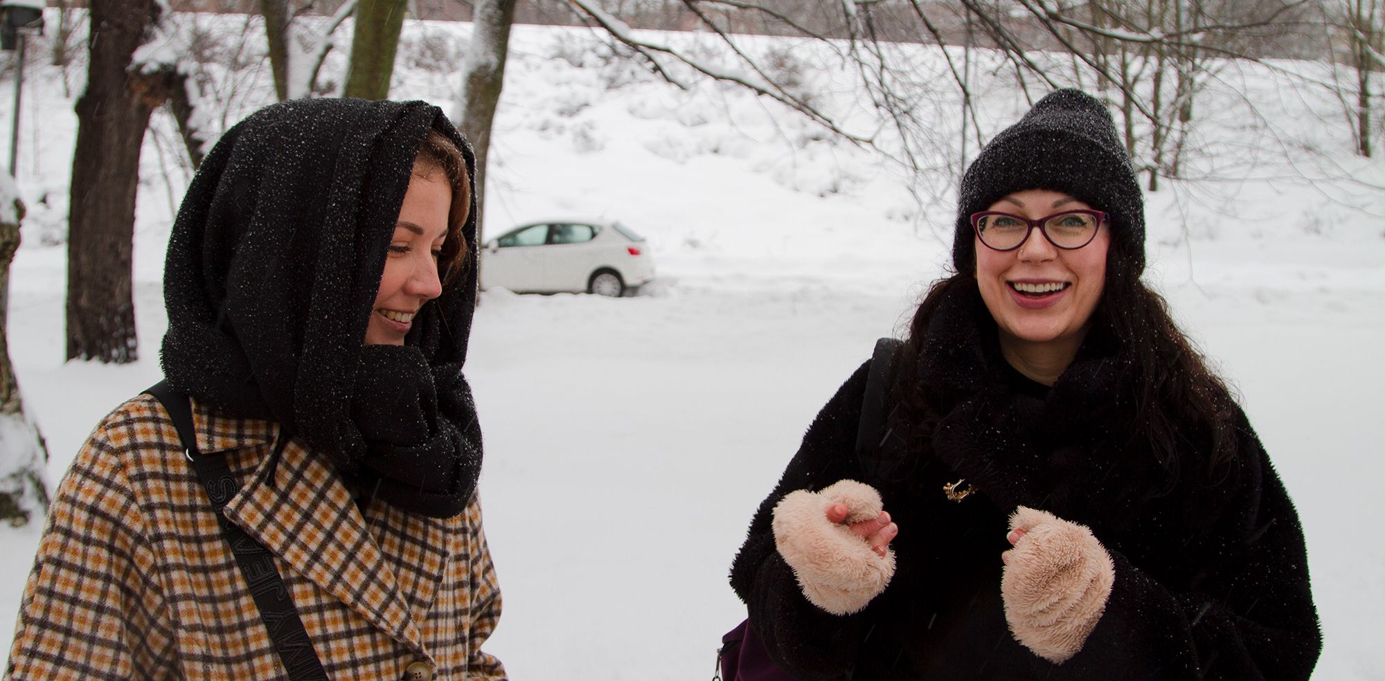 Две женщины улыбаются на фоне зимнего пейзажа (Kaksi naista hymyilevät, taustalla talvinen maisema)