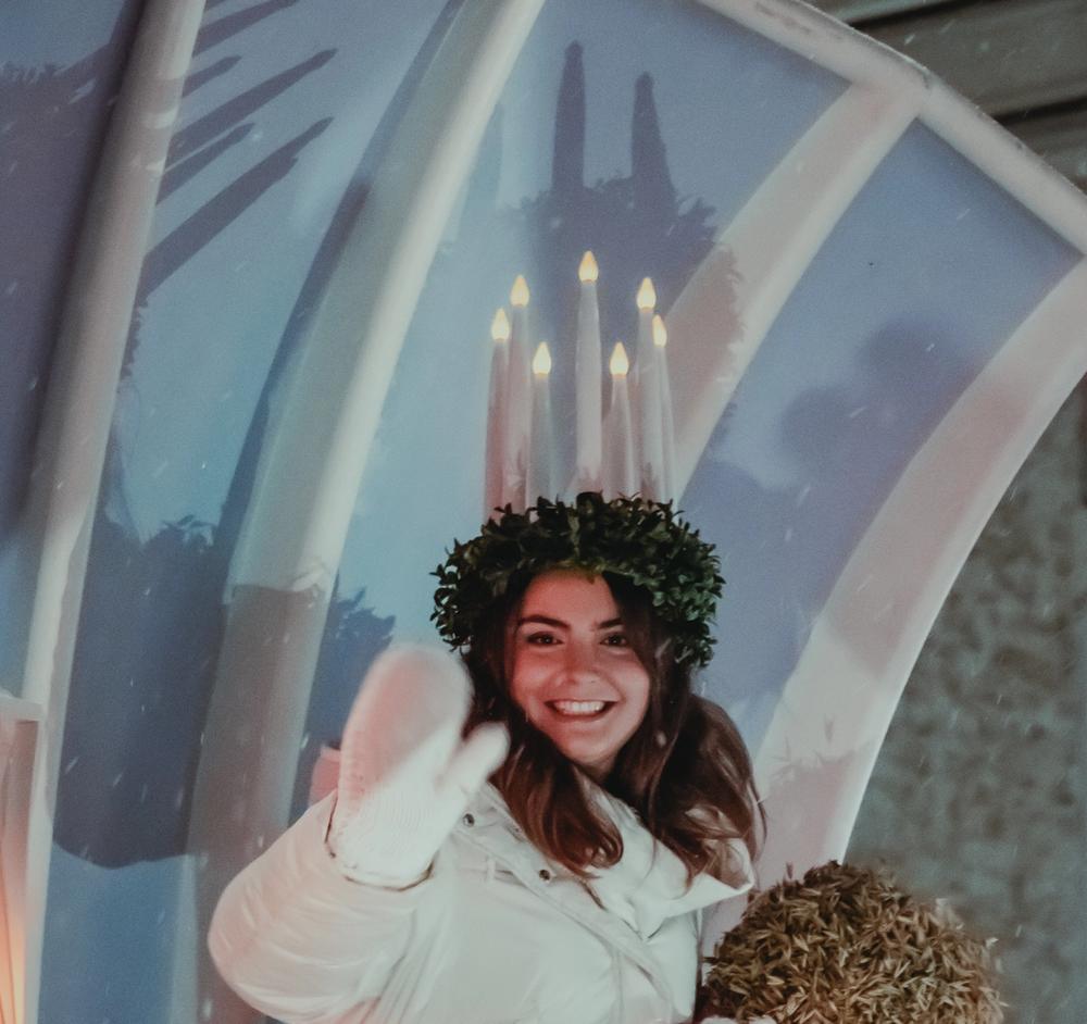 Люсия 2023 Мадлен Аморосо улыбается и машет рукой (Vuoden 2023 Lucia-neito Madeleine Amoroso heiluttaa yleisölle hymyillen)