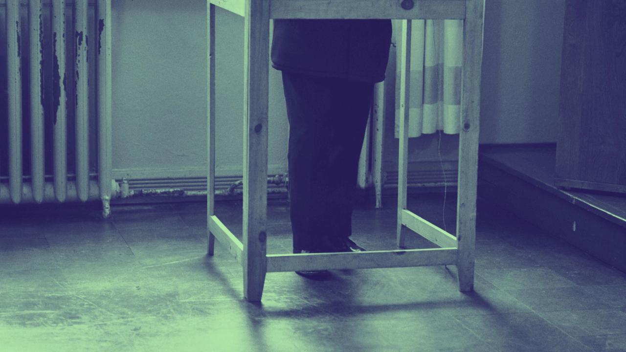 Kuva: Mies äänestyskopissa, vain jalat näkyvissä eduskuntavaalien äänestyspaikalla Oikokadun kansakoululla