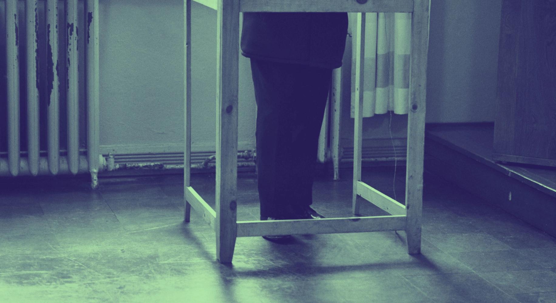 Kuva: Mies äänestyskopissa, vain jalat näkyvissä eduskuntavaalien äänestyspaikalla Oikokadun kansakoululla