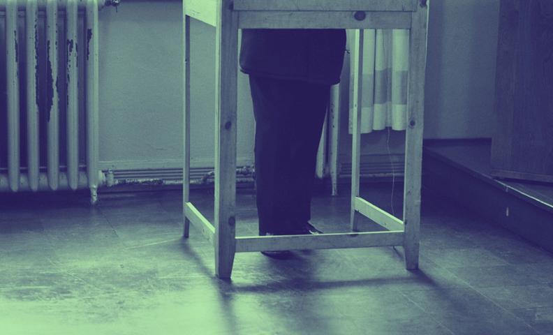 Kuva: Mies äänestyskopissa, vain jalat näkyvissä eduskuntavaalien äänestyspaikalla Oikokadun kansakoululla