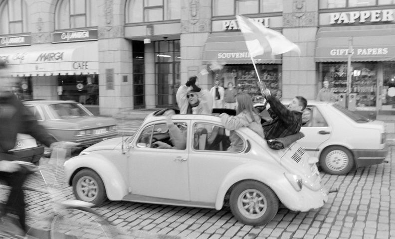 Люди празднуют и размахивают финским флагом в машине (Ihmiset juhlivat autossa heiluttaen Suomen lippua)