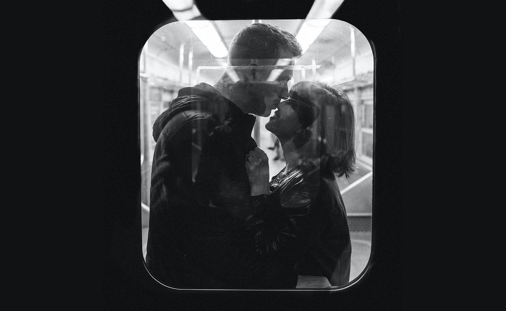 Пара обнимается в поезде, вид через окно вагона (Pariskunta halaamassa junassa ikkunan takaa kuvattuna)