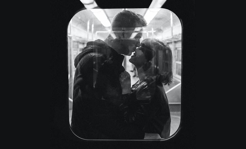 Пара обнимается в поезде, вид через окно вагона (Pariskunta halaamassa junassa ikkunan takaa kuvattuna)