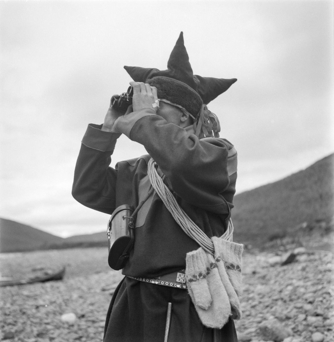 Человек в саамском костюме смотрит в бинокль (Saamenpukuun pukeutunut mies katsoo kiikareilla maisemaa)