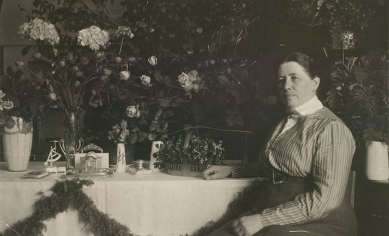 Фотография Миины Силланпяя, сидящей за столом (Kuva Miina Sillanpäästä istumassa ruokapöydän ääressä)