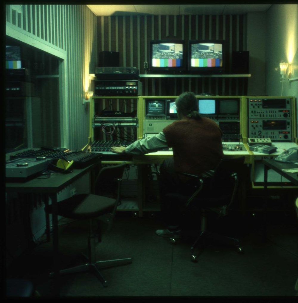 Kuvassa on studiotila. Ylähyllyllä on kaksi matkakokoista televisiota, joissa on meneillään Otaniemeen opiskelemaan-lähetys. Ylähyllyllä on myös kovaääniset sekä levysoitin. Pöydällä on lankapuhelin.