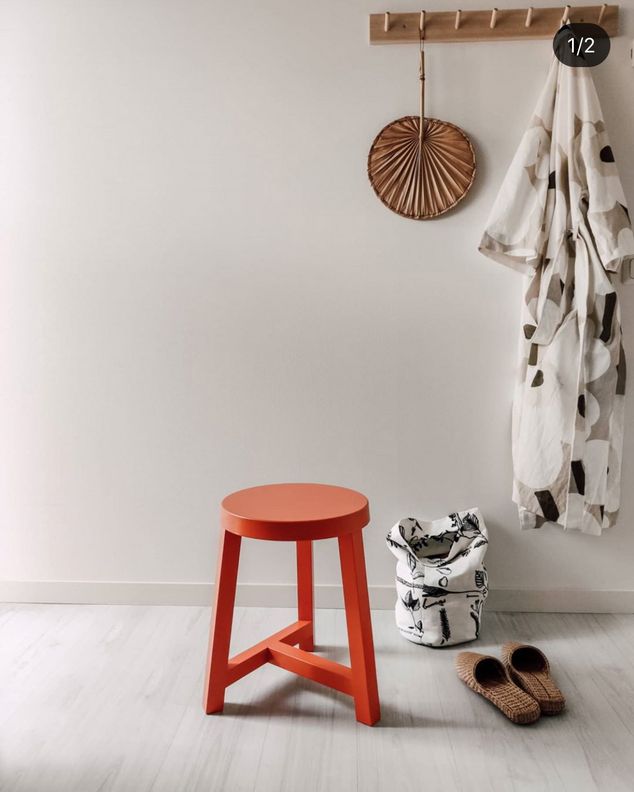 Интерьер: красный табурет, тапочки и одежда у стены (Sisustus: punainen jakkara, tohvelit ja vaatteet seinällä).