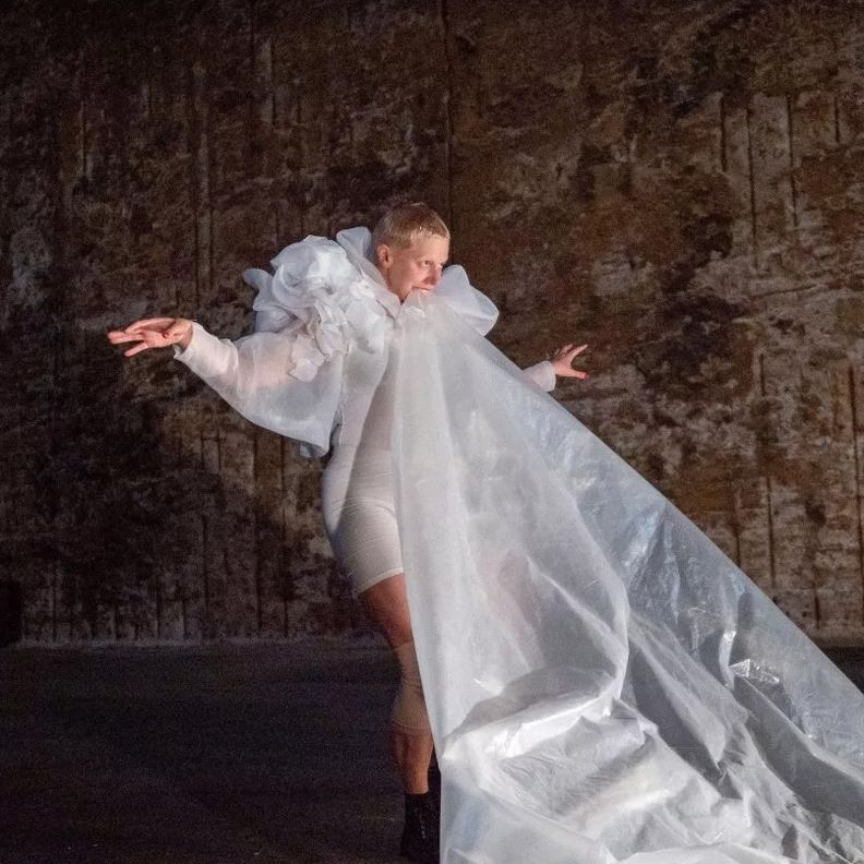 Перформер в белом с длинной тканью в индустриальном пространстве (Esiintyjä valkoisessa pitkän kankaan kanssa teollisessa tilassa)