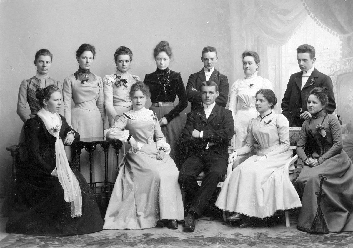 Mustavalkoinen valokuva ryhmästä ihmisiä vuonna 1899 tai 1900. Kuvassa on kaksitoista henkilöä, joista suurin osa on naisia. He poseeraavat muodollisesti studiossa, osa istuen ja osa seisten. Kaikilla on ajan tyylin mukaiset juhlapuvut. Taustalla näkyy verho ja koristeellinen sisustus. Kuvassa ovat insinööri Wesénin ja Alberta Wikstedtin häiden vieraat.