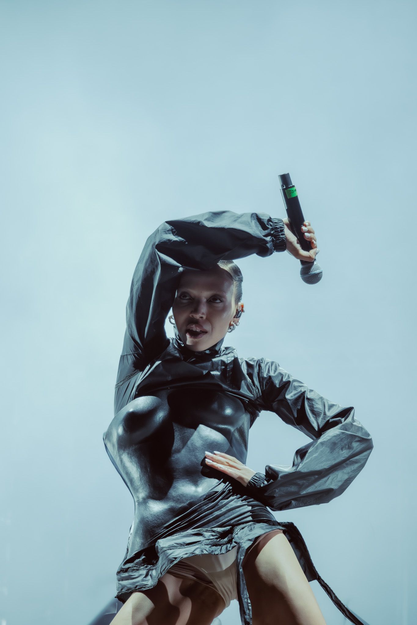 Певица на сцене в тёмном костюме с микрофоном в руке (Laulaja lavalla tummassa asussa mikrofonin kanssa).