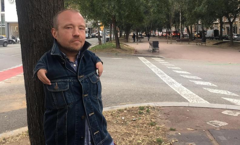 Мужчина стоит на улице, оперевшись на дерево (Mies seisoo kadulla puun runkoon nojaten)