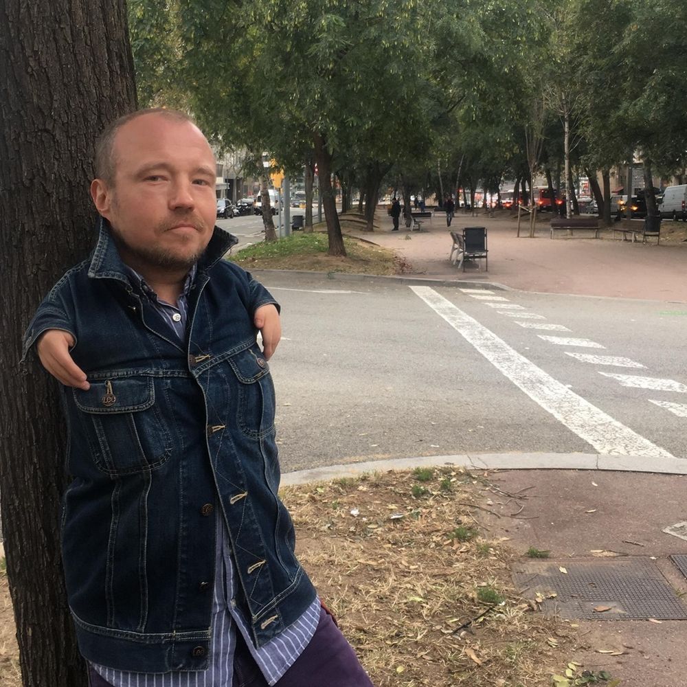 Мужчина стоит на улице, оперевшись на дерево (Mies seisoo kadulla puun runkoon nojaten)