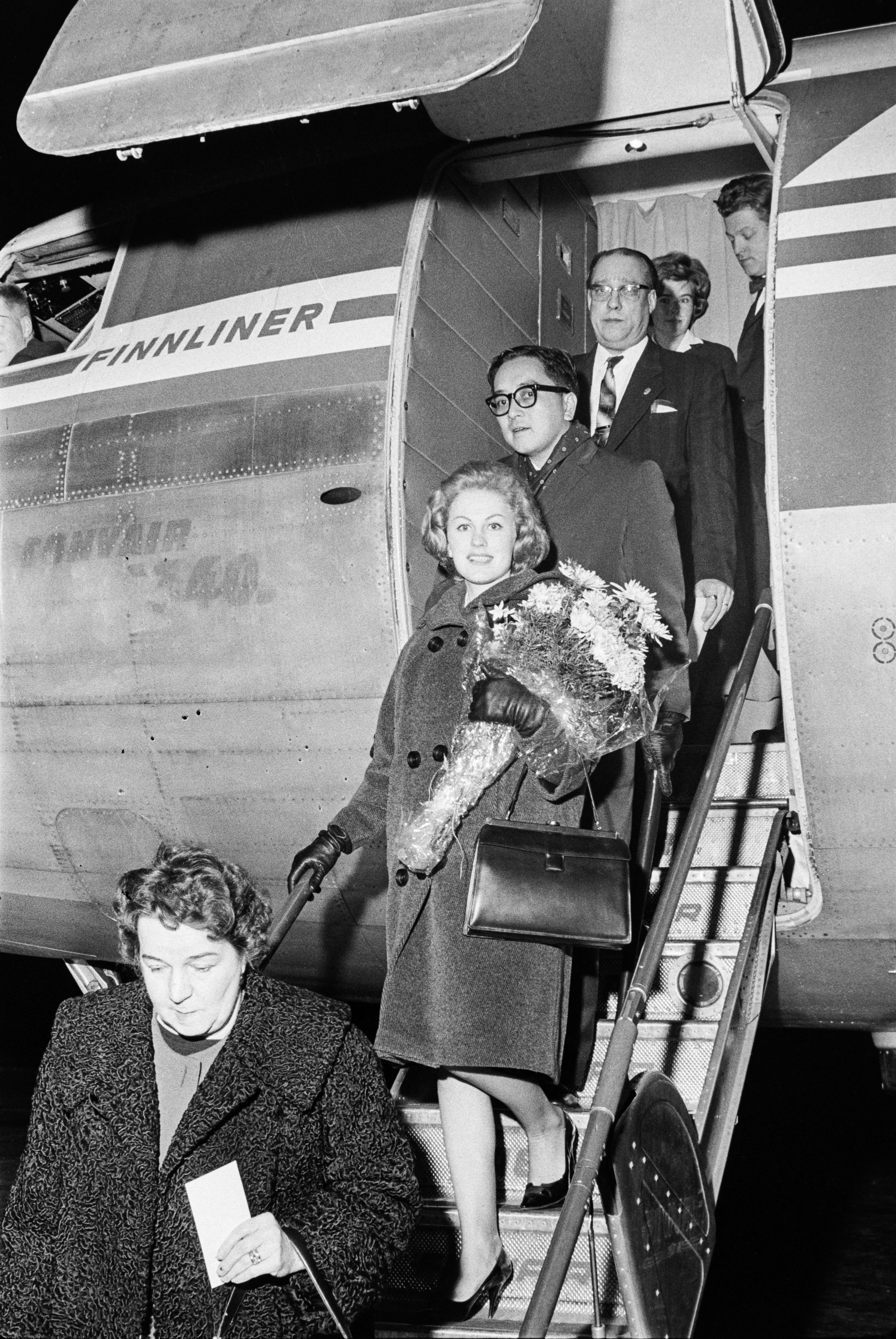 Арми Куусела с супругом спускаются по трапу самолета (Armi Kuusela aviomiehensä kanssa laskeutumassa lentokoneesta)