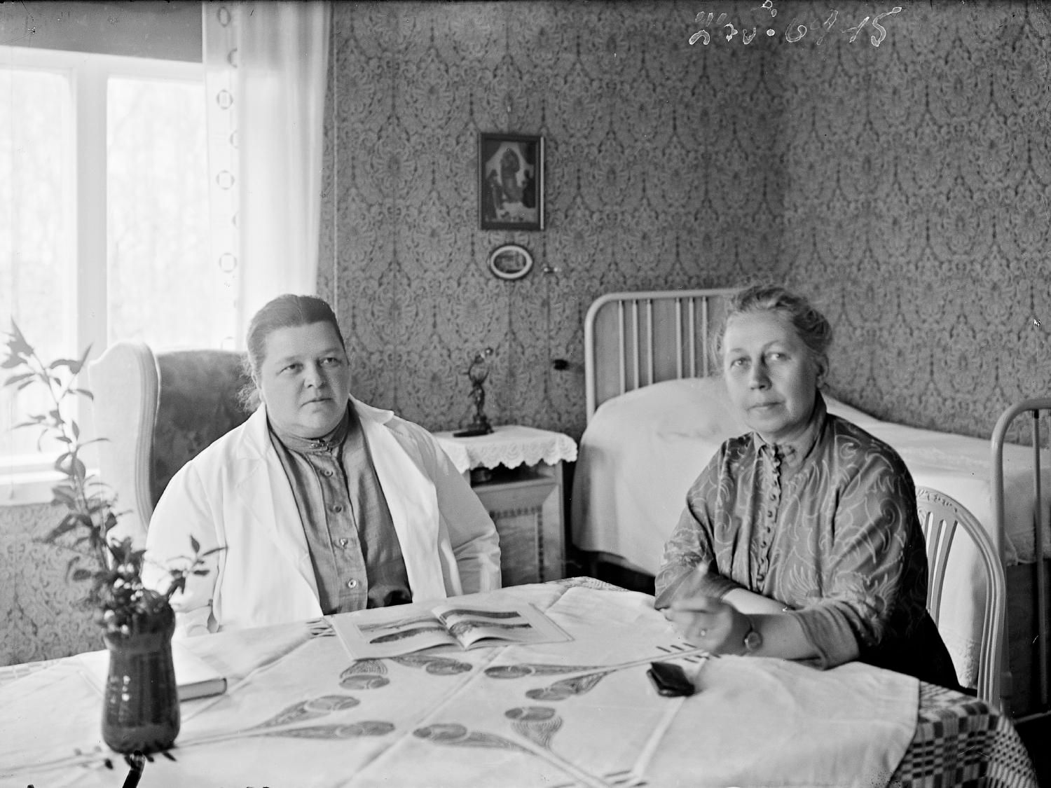 Ханна Парвиайнен и Виви Лённ сидя за столом (Hanna Parviainen ja Wivi Lönn istumassa pöydän ääressä)