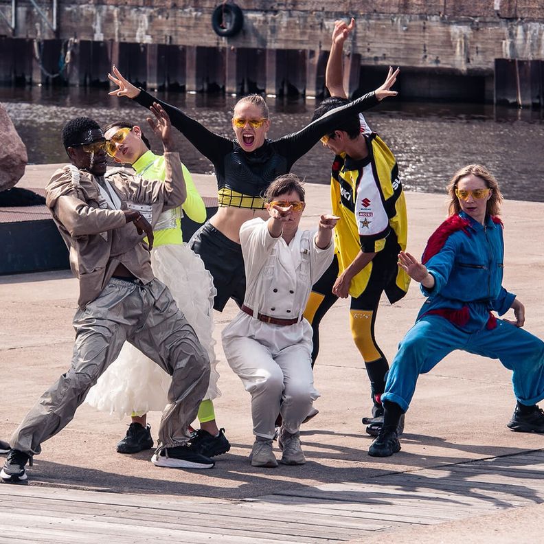 Группа танцоров в яркой одежде выступает на улице у воды (Ryhmä tanssijoita kirkkaissa vaatteissa esiintyy ulkona veden äärellä)