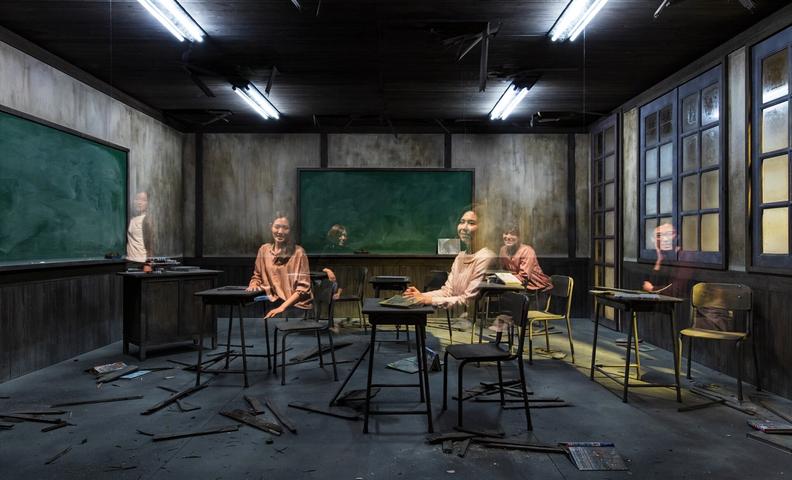 Инсталляция тёмного класса с поломанной мебелью и призрачными фигурами. (Synkkä luokkahuone haamumaisine hahmoineen)