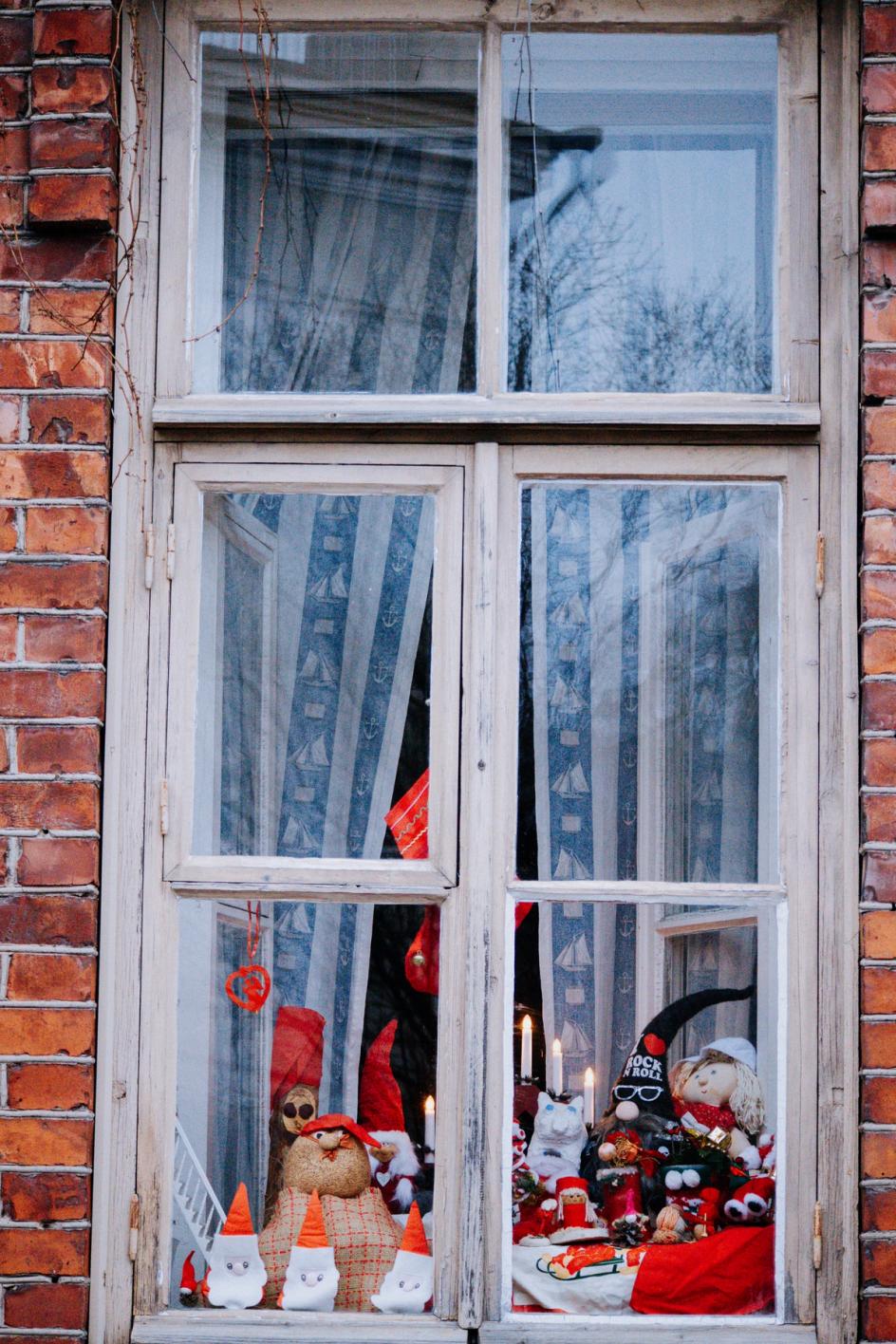 На фотографии изображено окно кирпичного дома, украшенное праздничным новогодним декретом (Kuvassa on tiilitalon ikkuna, joka on koristeellisesti sisustettu joulukoristeilla).