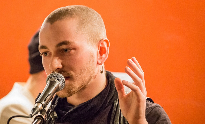 Человек с микрофоном говорит, микрофон стоит перед ним. Ihminen mikrofonin kanssa, puhuu tai esittää yleisölle.