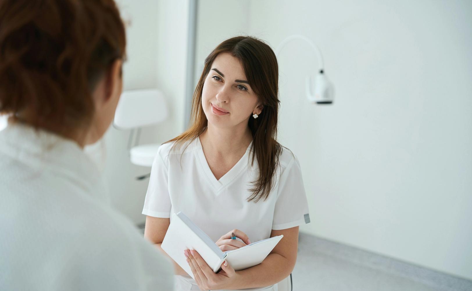 Женщина-врач слушает пациентку и делает записи (Lääkäri kuuntelee potilasta ja tekee muistiinpanoja)