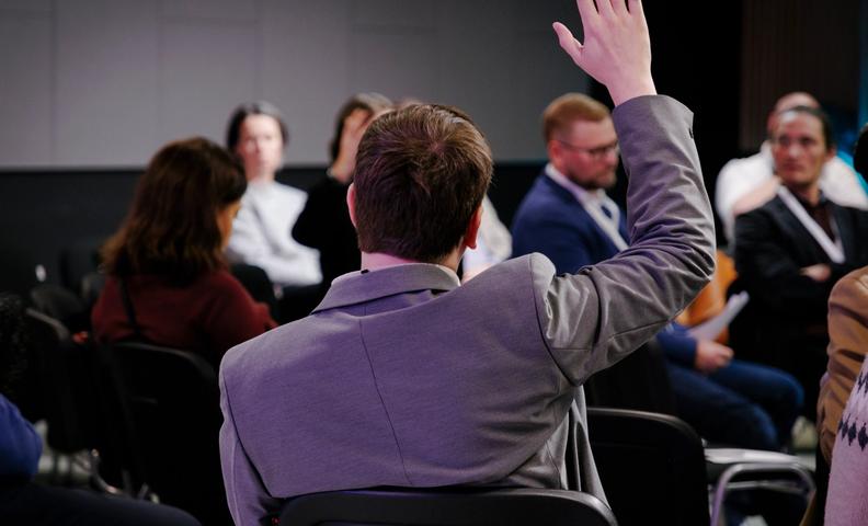 Участник поднимает руку на дискуссии CulturalistTalks. (Osallistuja nostaa kätensä CulturalistTalks-keskustelussa.)