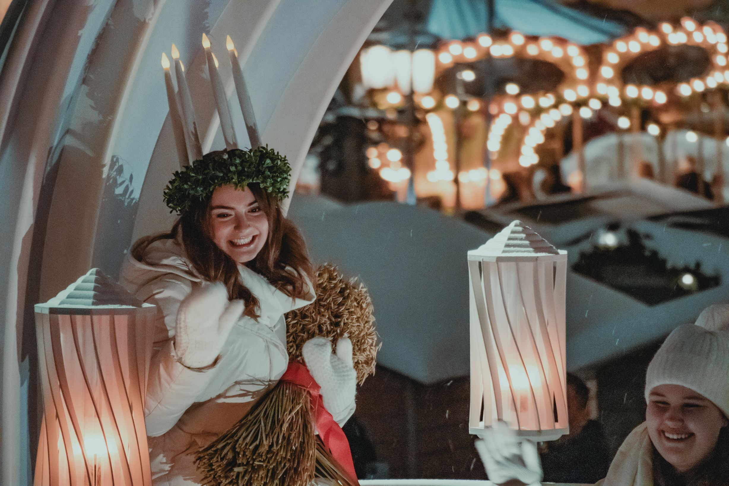 Suomen vuoden 2023 Lucia-neito Madeleine Amoroso istuu vaunuissaan päässään kynttiläkruunu.